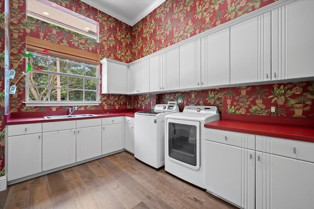 laundry room featuring cabinets, crown molding, sink, washer and dryer, and wood-type flooring