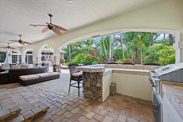 view of patio / terrace with ceiling fan, exterior kitchen, an outdoor hangout area, grilling area, and a bar