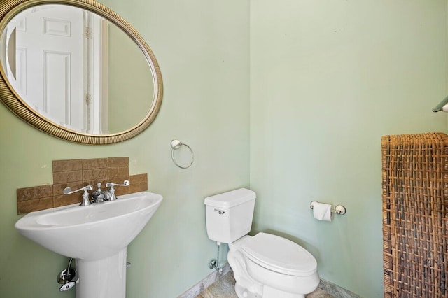 bathroom featuring toilet, sink, and tasteful backsplash