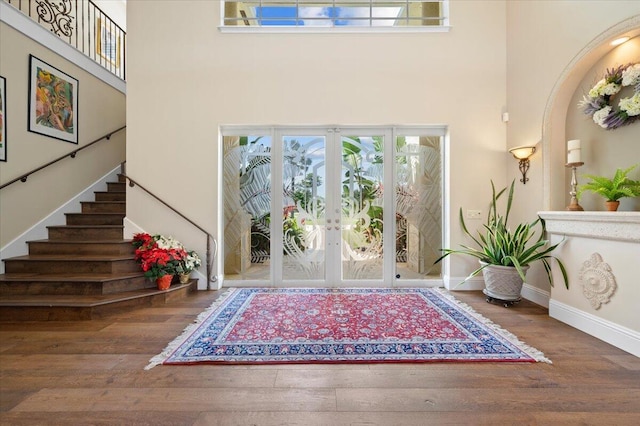 entryway with french doors, a towering ceiling, and hardwood / wood-style flooring