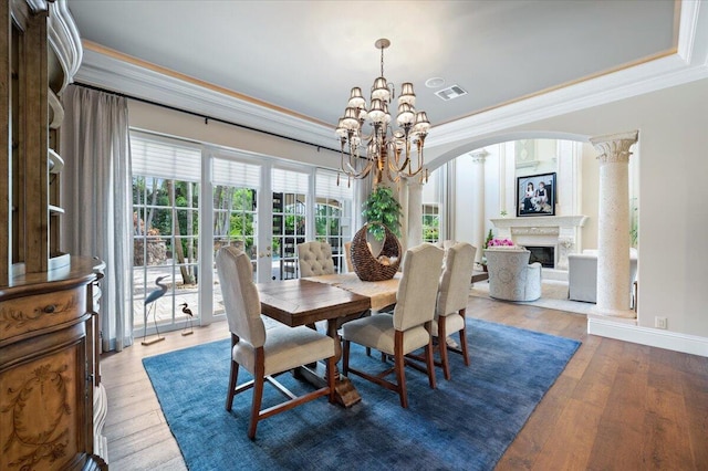 dining room featuring french doors, a notable chandelier, decorative columns, hardwood / wood-style floors, and ornamental molding