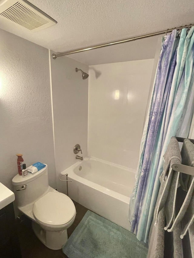 full bathroom with shower / bath combination with curtain, vanity, a textured ceiling, and toilet