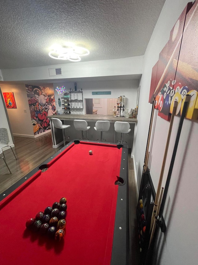 recreation room with bar area, hardwood / wood-style floors, a textured ceiling, and billiards