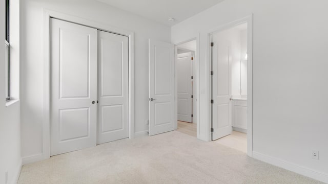 unfurnished bedroom with light colored carpet and a closet