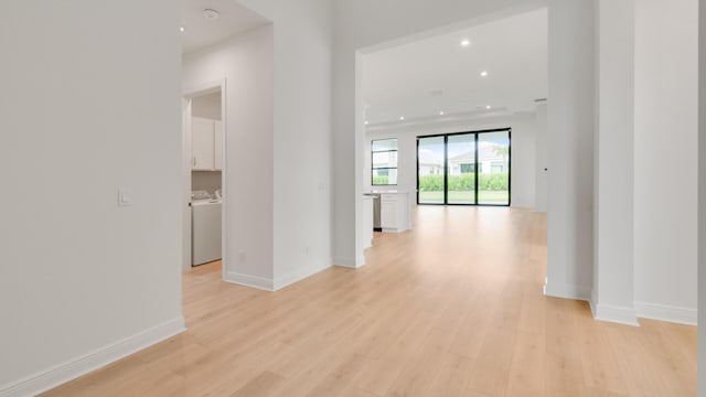 corridor with light hardwood / wood-style flooring and independent washer and dryer