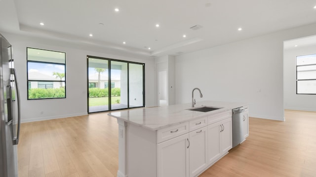 kitchen with light stone countertops, sink, an island with sink, white cabinets, and appliances with stainless steel finishes