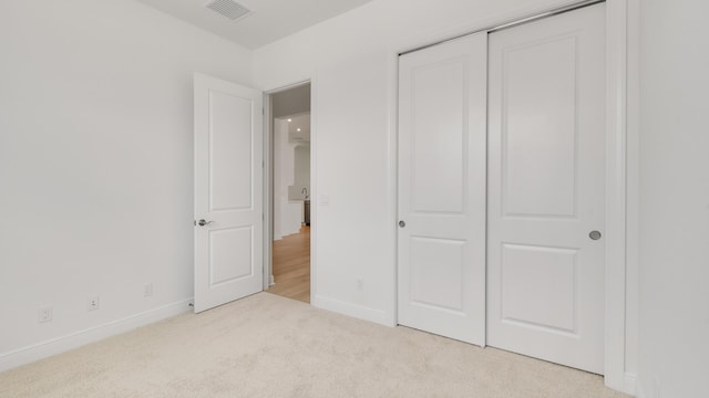 unfurnished bedroom featuring a closet and light colored carpet