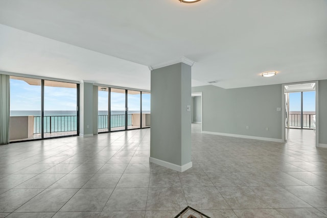 tiled empty room featuring plenty of natural light, expansive windows, and a water view