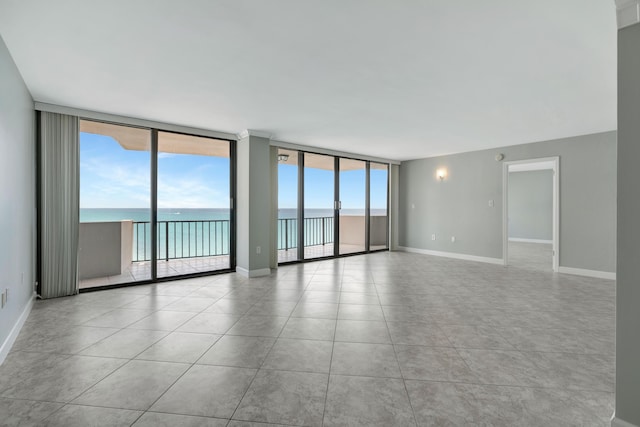 spare room featuring light tile patterned flooring, expansive windows, and a water view