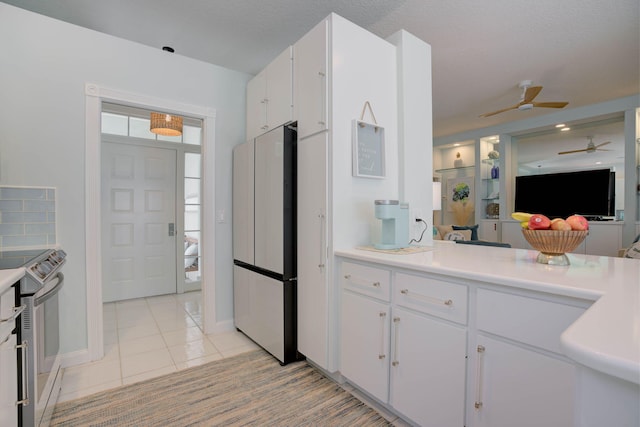 kitchen with refrigerator, a textured ceiling, electric stove, white cabinetry, and light tile patterned flooring