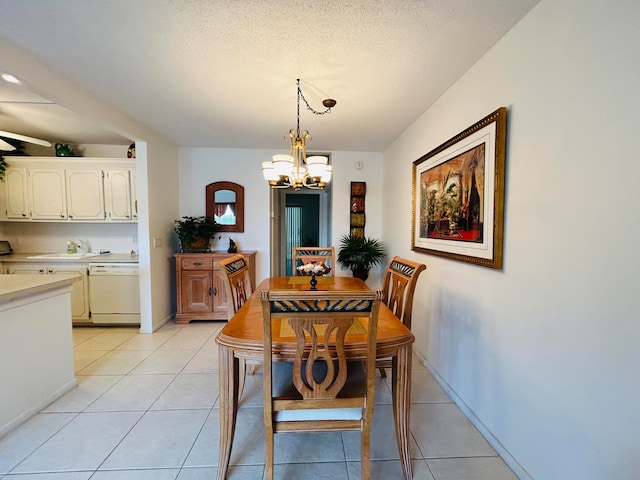 dining space with sink, light tile patterned floors, a textured ceiling, and an inviting chandelier