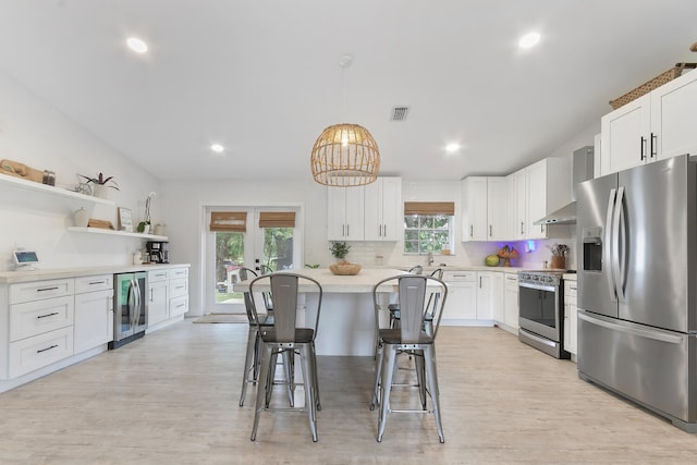 kitchen with light wood-type flooring, tasteful backsplash, stainless steel appliances, and white cabinets