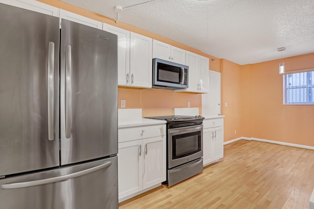 kitchen with white cabinets, appliances with stainless steel finishes, a textured ceiling, and hanging light fixtures