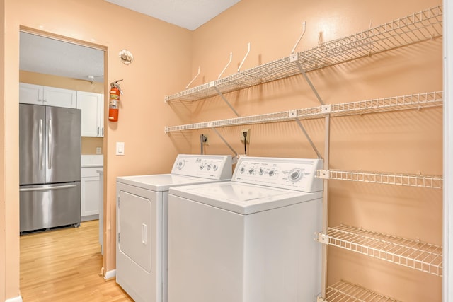 clothes washing area featuring washing machine and dryer and light hardwood / wood-style flooring