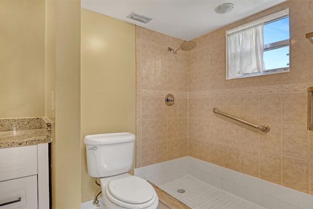 bathroom featuring tiled shower, vanity, and toilet