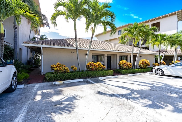 exterior space featuring uncovered parking, a tiled roof, and stucco siding