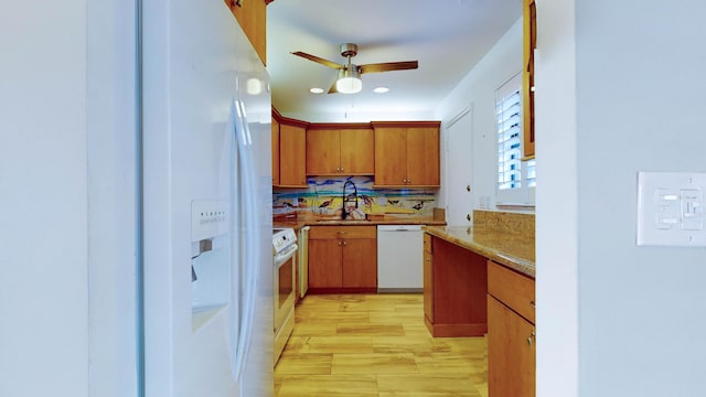 kitchen featuring white appliances, a sink, a ceiling fan, light wood-style floors, and brown cabinetry