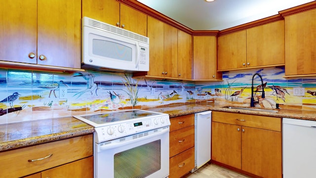 kitchen featuring light stone counters, white appliances, a sink, and decorative backsplash