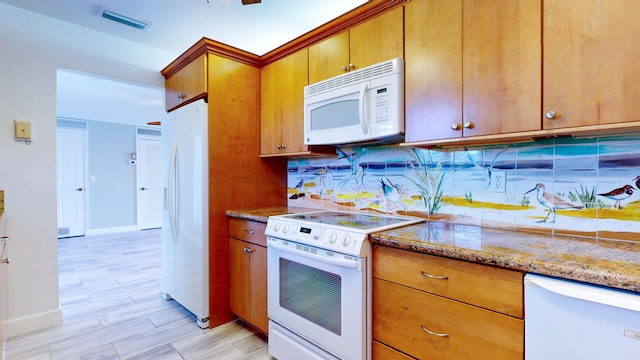 kitchen featuring visible vents, backsplash, brown cabinetry, light stone countertops, and white appliances