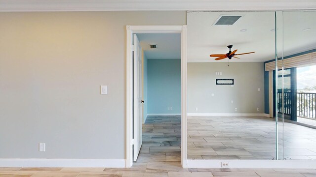 spare room featuring a ceiling fan, visible vents, crown molding, and baseboards