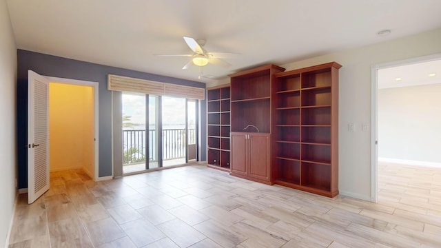 empty room featuring light wood-style floors, a ceiling fan, and baseboards