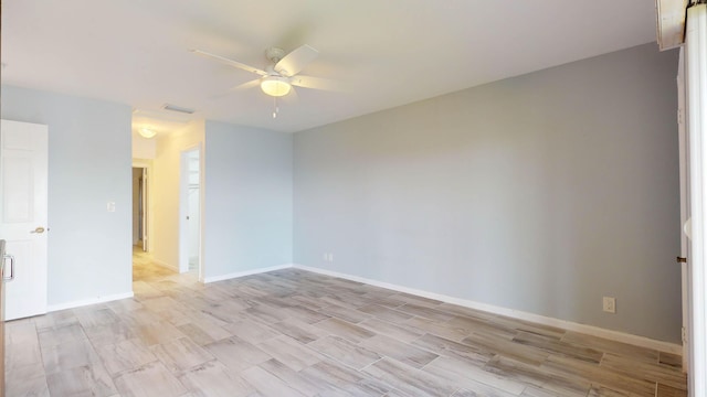 empty room with visible vents, ceiling fan, light wood finished floors, and baseboards