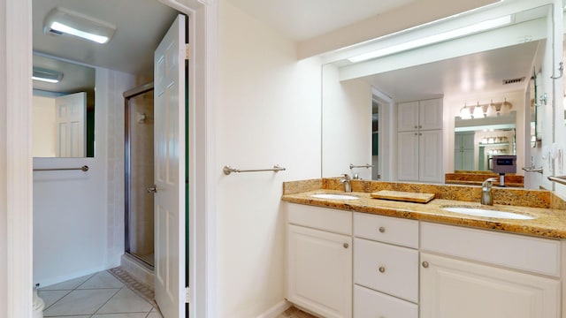 full bathroom featuring double vanity, a stall shower, tile patterned flooring, and a sink