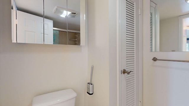 bathroom featuring toilet, an enclosed shower, and a closet