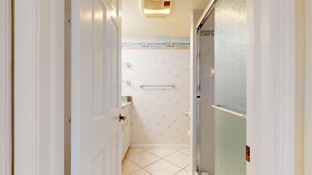 bathroom featuring tile patterned flooring, toilet, baseboards, tiled shower, and wallpapered walls