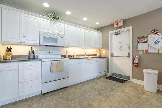 kitchen featuring white appliances, dark countertops, recessed lighting, and white cabinets