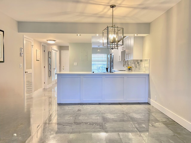 kitchen with stainless steel refrigerator, white cabinetry, hanging light fixtures, backsplash, and a chandelier