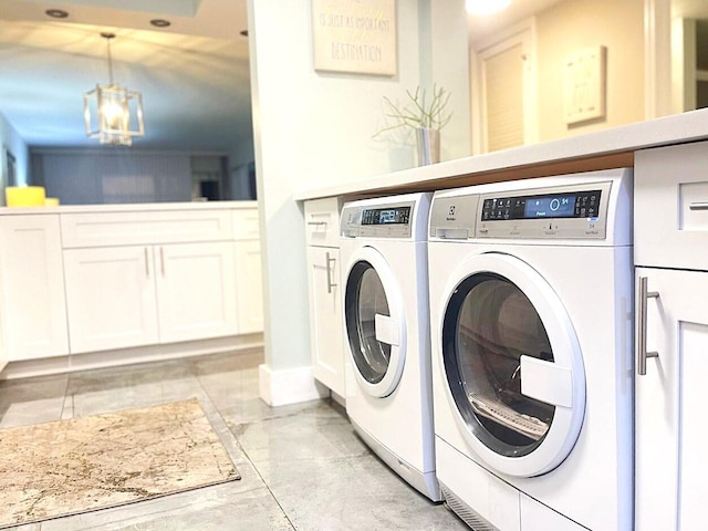 clothes washing area with washing machine and clothes dryer, cabinet space, and baseboards