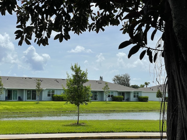 rear view of property featuring a water view and a lawn