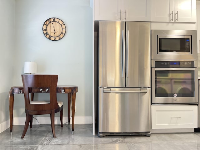 kitchen featuring appliances with stainless steel finishes, white cabinetry, and baseboards
