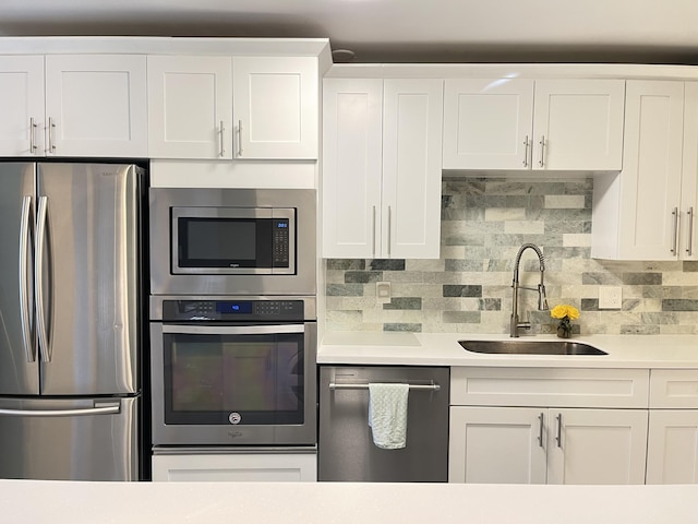kitchen featuring appliances with stainless steel finishes, a sink, light countertops, and white cabinetry