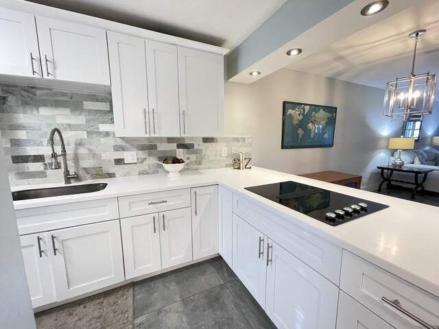 kitchen with a sink, black electric stovetop, decorative backsplash, light countertops, and recessed lighting