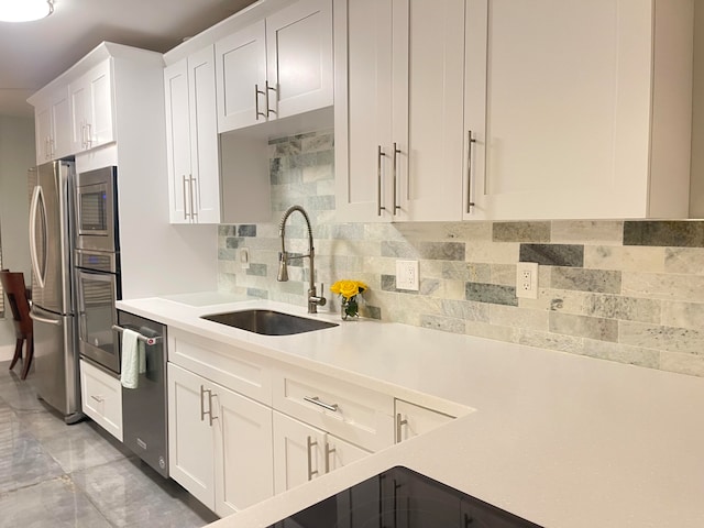 kitchen with backsplash, white cabinetry, sink, and appliances with stainless steel finishes