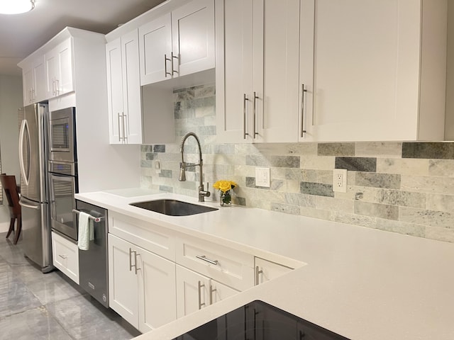 kitchen featuring a sink, stainless steel appliances, light countertops, white cabinets, and tasteful backsplash
