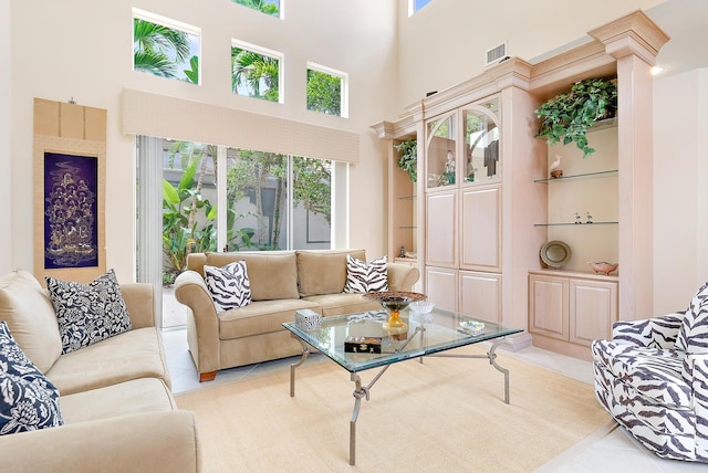 living room featuring built in shelves, tile patterned floors, decorative columns, and a towering ceiling