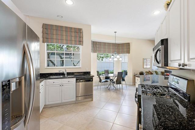 kitchen featuring white cabinets, stainless steel appliances, hanging light fixtures, and a wealth of natural light