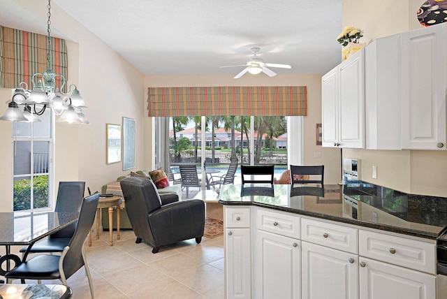 kitchen featuring dark stone countertops, white cabinetry, ceiling fan, and light tile patterned floors