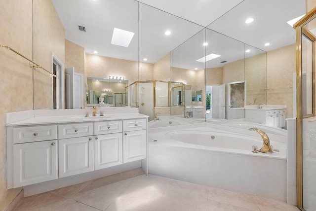 bathroom with a skylight, vanity, tile patterned flooring, and a bathing tub