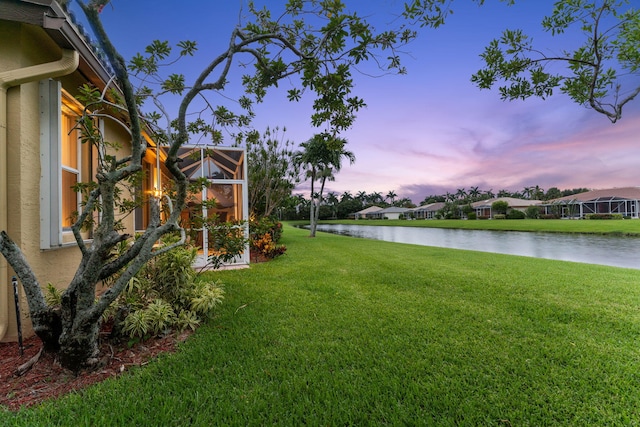 yard at dusk featuring a water view