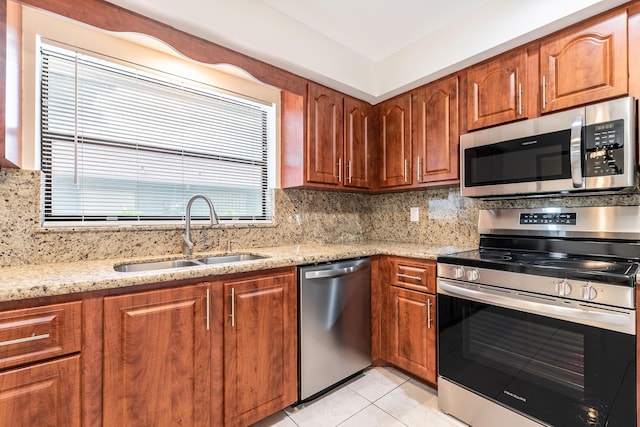 kitchen featuring decorative backsplash, sink, light stone countertops, and stainless steel appliances