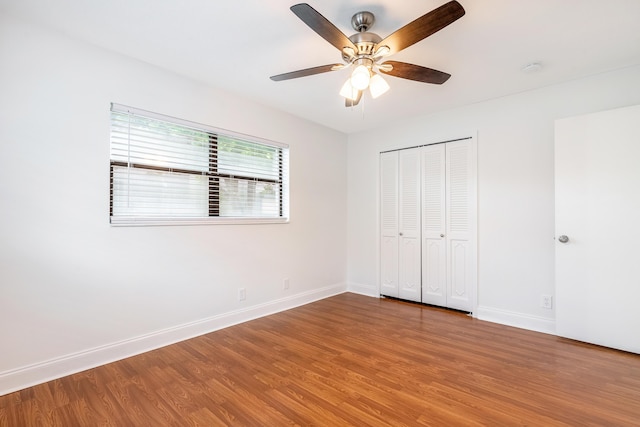 unfurnished bedroom featuring hardwood / wood-style floors, ceiling fan, and a closet