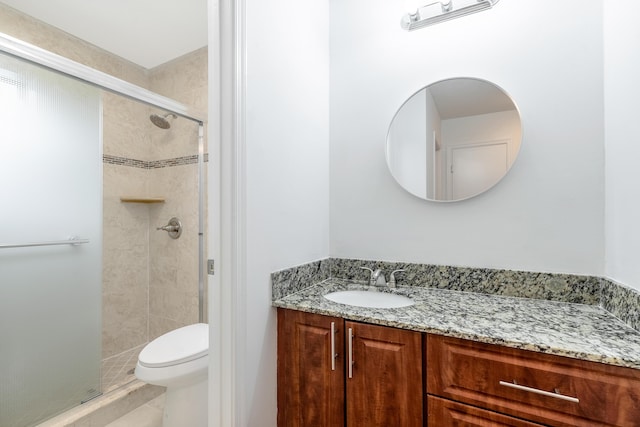 bathroom featuring vanity, toilet, and a shower with shower door