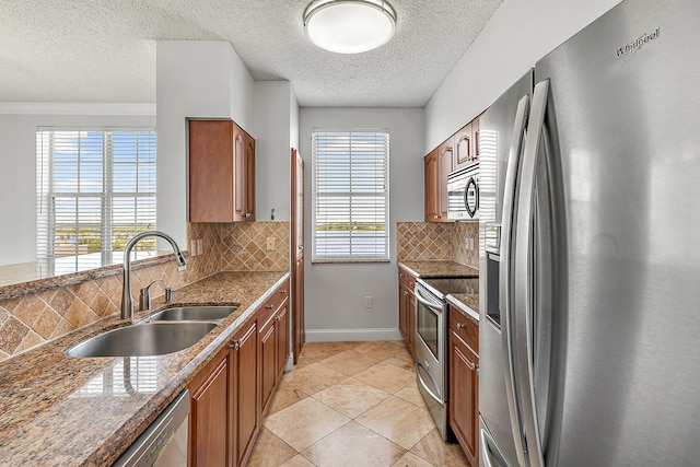 kitchen featuring sink, decorative backsplash, stainless steel appliances, and light tile patterned floors