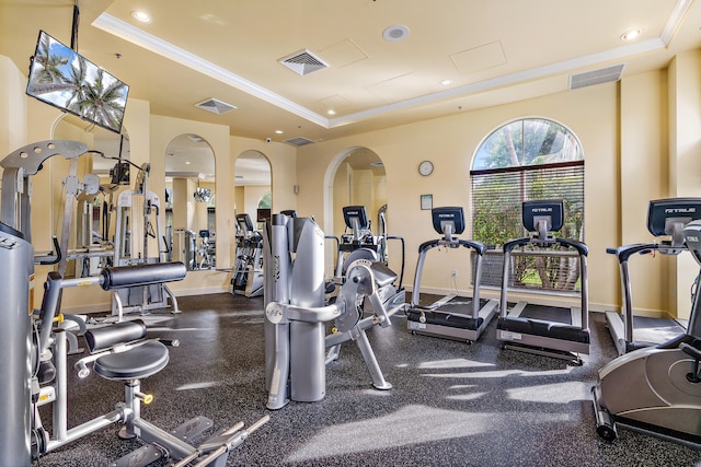 workout area featuring a raised ceiling and ornamental molding