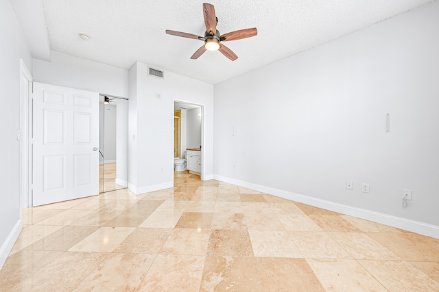 unfurnished bedroom featuring ensuite bathroom, a textured ceiling, light tile patterned floors, and ceiling fan