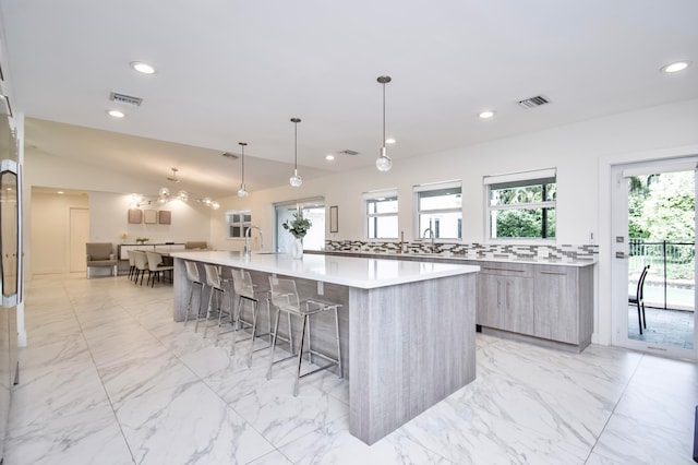 kitchen with a wealth of natural light, light tile patterned flooring, a spacious island, and a kitchen bar